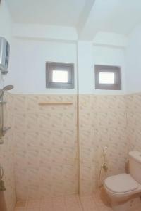 y baño con ducha, aseo y 2 ventanas. en Indeewaree Villa, en Kamburugamuwa