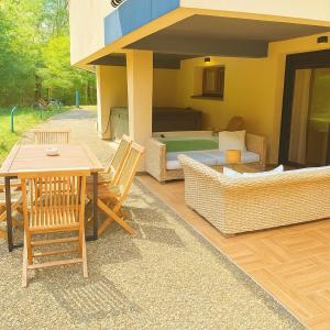 a patio with a table and chairs in front of a house at L'orée du bois - Contis - Ocean and Spa in Saint-Julien-en-Born
