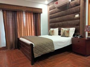 a bedroom with a large bed with a wooden headboard at Canal View Hotel in Dargai