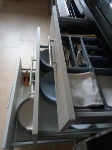 an open cabinet with plates and utensils in a kitchen at Casa El Rincón in Santa Eulalia de las Manzanas