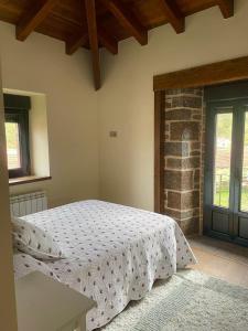 a bedroom with a bed and a brick wall at Casa El Rincón in Santa Eulalia de las Manzanas