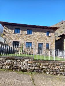 a stone house with a fence in front of it at Casa El Rincón in Santa Eulalia de las Manzanas