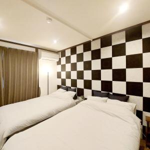2 camas en una habitación con una pared a cuadros en B-STAY ikeda, en Kumamoto