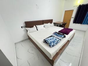 um quarto com uma cama com lençóis brancos e almofadas roxas em eden homestay em Munnar