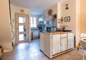 a large kitchen with white cabinets and a door at Maison cosy 75m² – Porquerolles Immobilier in Porquerolles +4 photos