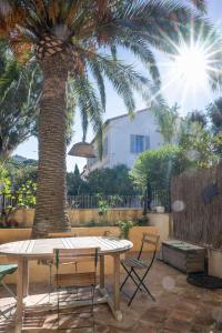 a table and chairs in front of a palm tree at Maison cosy 75m² – Porquerolles Immobilier in Porquerolles