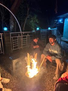 达兰萨拉Friend circle cafe and homestay dharamsala的晚上，两个男人围坐在火堆旁 更多4张照片
