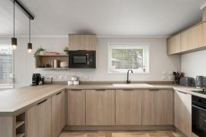 a kitchen with wooden cabinets and a microwave at Modern Lodge nr Ilfracombe & Beaches in West Down +18 photos