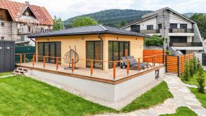 ein Haus mit einer großen Terrasse in einem Garten in der Unterkunft A-Frame Villas in Buşteni