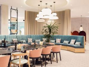 a restaurant with a blue couch and tables and chairs at Pullman Madrid Airport & Feria in Madrid