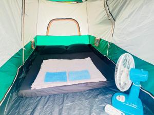 a green and white tent with a mattress and a fan at Veha Koh Rong in Kaôh Rŭng