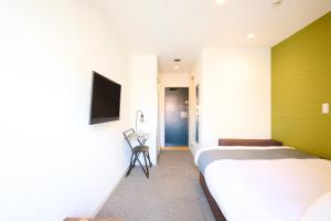 a bedroom with two beds and a tv on the wall at Hotel Stripe 札幌 in Sapporo