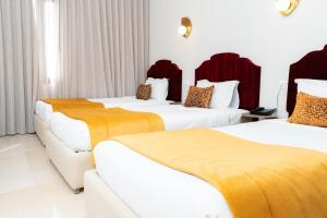 two beds in a hotel room with yellow and white at hôtel LE PACHA in Tunis