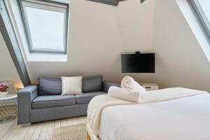 ein Zimmer mit einem Bett, einer Couch und einem Fernseher in der Unterkunft Studio mansardé à deux pas de la Citadelle in Lille