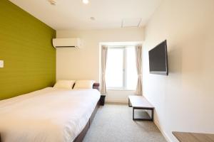 a bedroom with two beds and a tv at Hotel Stripe 札幌 in Sapporo +12 photos