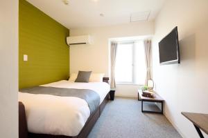 a hotel room with two beds and a tv at Hotel Stripe 札幌 in Sapporo