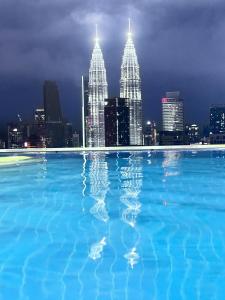 uma piscina com um horizonte da cidade à noite em The Luxe Infinitum Suite KLCC em Kuala Lumpur