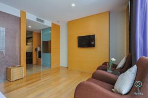 a living room with two chairs and a tv on a wall at Empire Suites Subang by MyKey in Subang Jaya