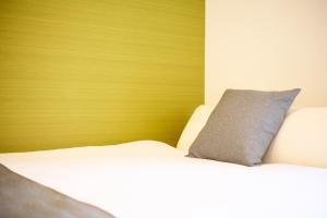 a bedroom with a white bed with a wooden headboard at Hotel Stripe 札幌 in Sapporo