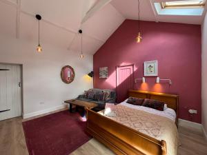 a bedroom with a bed and a red wall at Cosy Northumberland Studio Cottage in Thropton