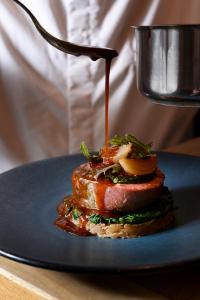 un morceau de viande avec de la sauce sur une assiette bleue dans l'établissement Hôtel Taggât, à Lyon
