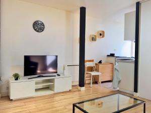 a living room with a tv and a glass table at Le Beige in Le Mans