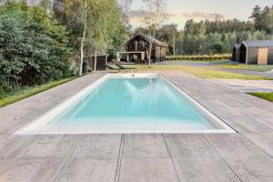 an infinity pool in a yard with a house in the background at Ostoja Warmia in Stawiguda
