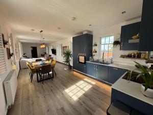 cocina con armarios azules y mesa y sala de estar en Leishman Views, en Itchen Abbas