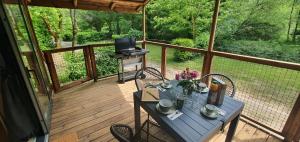 a porch with a table and chairs and a television at Camping le Moulin de David -Gaugeac Monpazier 24540 - Cabane -Mobil-home 3 et 2 chambres in Gaugeac