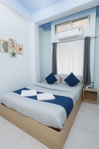 a bedroom with a large bed with blue pillows at Urban Suites Silpukhuri in Guwahati