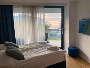 a bedroom with a bed and a large window at Seaside Park Apartament z widokiem na morze in Kołobrzeg