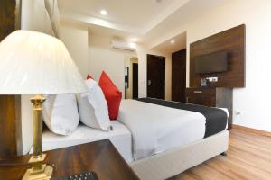 a hotel room with a bed and a desk with a lamp at HOTEL O NEW AARKAY INN & SUITES in Jalandhar