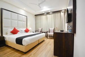 a hotel room with a bed and a table and chairs at HOTEL O NEW AARKAY INN & SUITES in Jalandhar