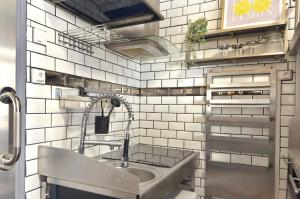 a sink in a kitchen with white tiled walls at Le Corsaire in Angers