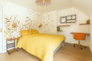 Un dormitorio con una cama amarilla con pájaros en la pared en Gîte Youna - Nature et charme breton entre Lizio et Josselin, en Lizio