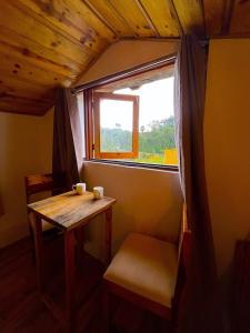 a small table and chair in a room with a window at Arameh-A Boutique Orchard Retreat Near Kasauli in Rājgarh