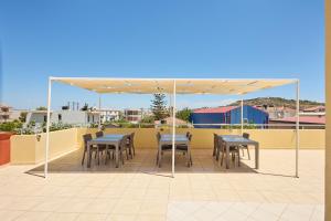 Un patio con mesas y sillas bajo un dosel. en ChioSmart Kontari Apartments, en Chios
