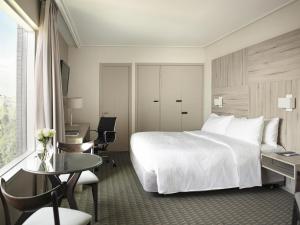 una camera d'albergo con un letto, una scrivania e un tavolo di Pullman Santiago Vitacura a Santiago