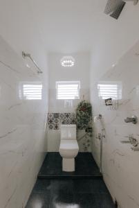 La salle de bains blanche est pourvue de toilettes et d'une plante. dans l'établissement Amrai by Kivaara, à Kishangarh 35 autres photos