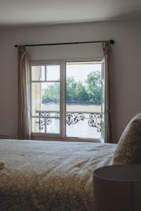 a bedroom with a bed and a large window at Logis de Belle Rive in Saint-Sulpice-de-Faleyrens