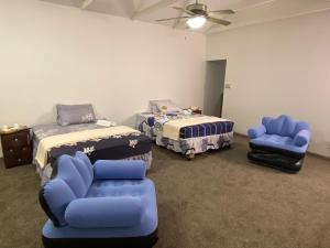 a room with two beds and chairs and a ceiling fan at Fiet Star in Midrand