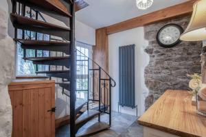 a spiral staircase in a room with a clock at Caldey View - 3 Bed - Hot Tub - Penally - Tenby in Penally