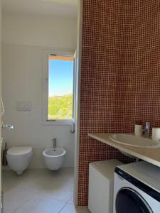 a bathroom with a toilet and a sink and a washing machine at Splendida vista mozzafiato Costa Rossa Sardegna in Isola Rossa