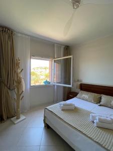 a bedroom with a bed with white sheets and a window at Splendida vista mozzafiato Costa Rossa Sardegna in Isola Rossa