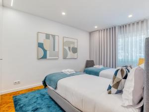 a bedroom with two beds and a blue rug at Vita Portucale ! Almada Trendy Retreat in Almada