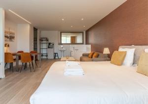 a bedroom with a large white bed and a living room at Acropolis - Luxury Appartments I Hotelservice and parking in Middelkerke