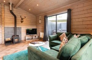 a living room with a green couch and a fireplace at Landal Aysgarth in Aysgarth
