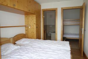a bedroom with a white bed with a wooden wall at Plein Ciel VA 021 MOUNTAIN apartment 8 pers in Veysonnaz
