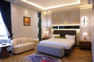 a bedroom with a king sized bed and a chair at Le Aura Grand Hotel in Lahore