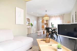 ein Wohnzimmer mit einem weißen Sofa und einem Fernseher in der Unterkunft Minimaliste Oasis - Golf & Spa in Saint Lo